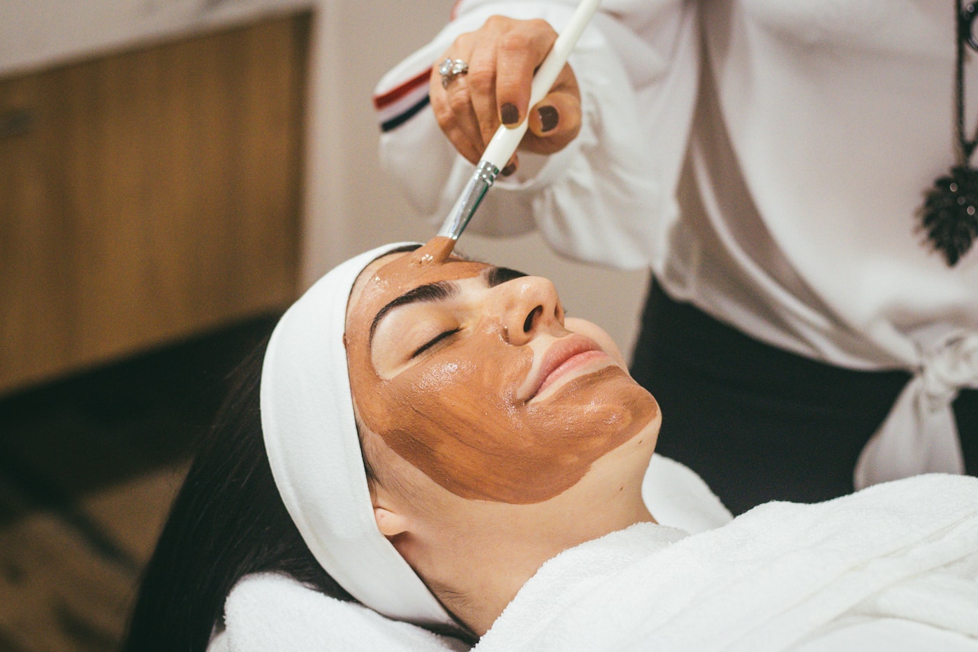 Profissional aplicando máscara facial em cliente